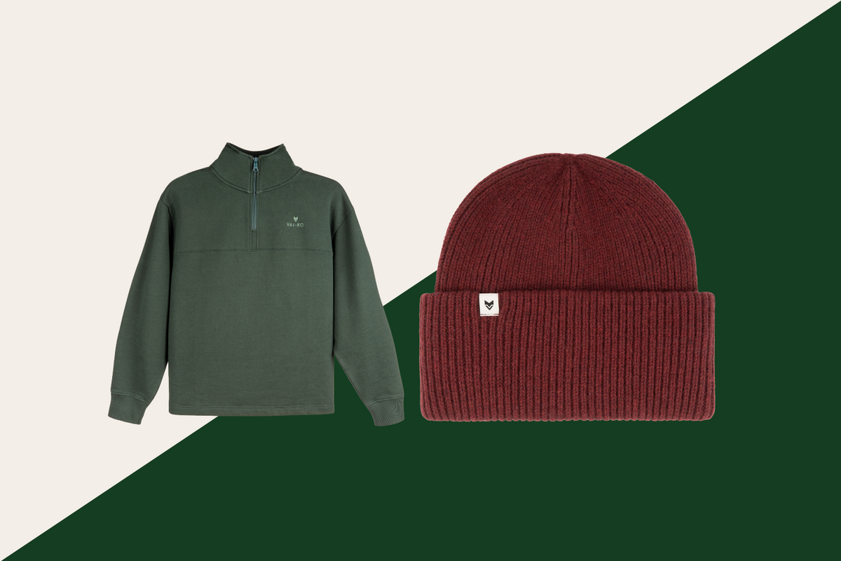A green quarter-zip pullover and a maroon knit beanie are displayed side by side on a split cream and dark green background.