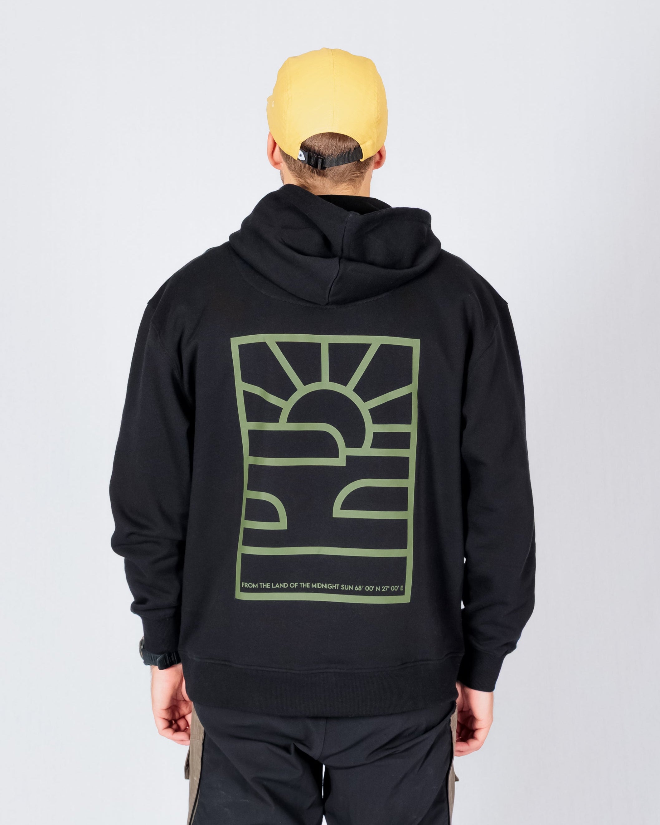 Person wearing a yellow cap, black hoodie with a green graphic, and two-tone cargo pants, seen from behind.