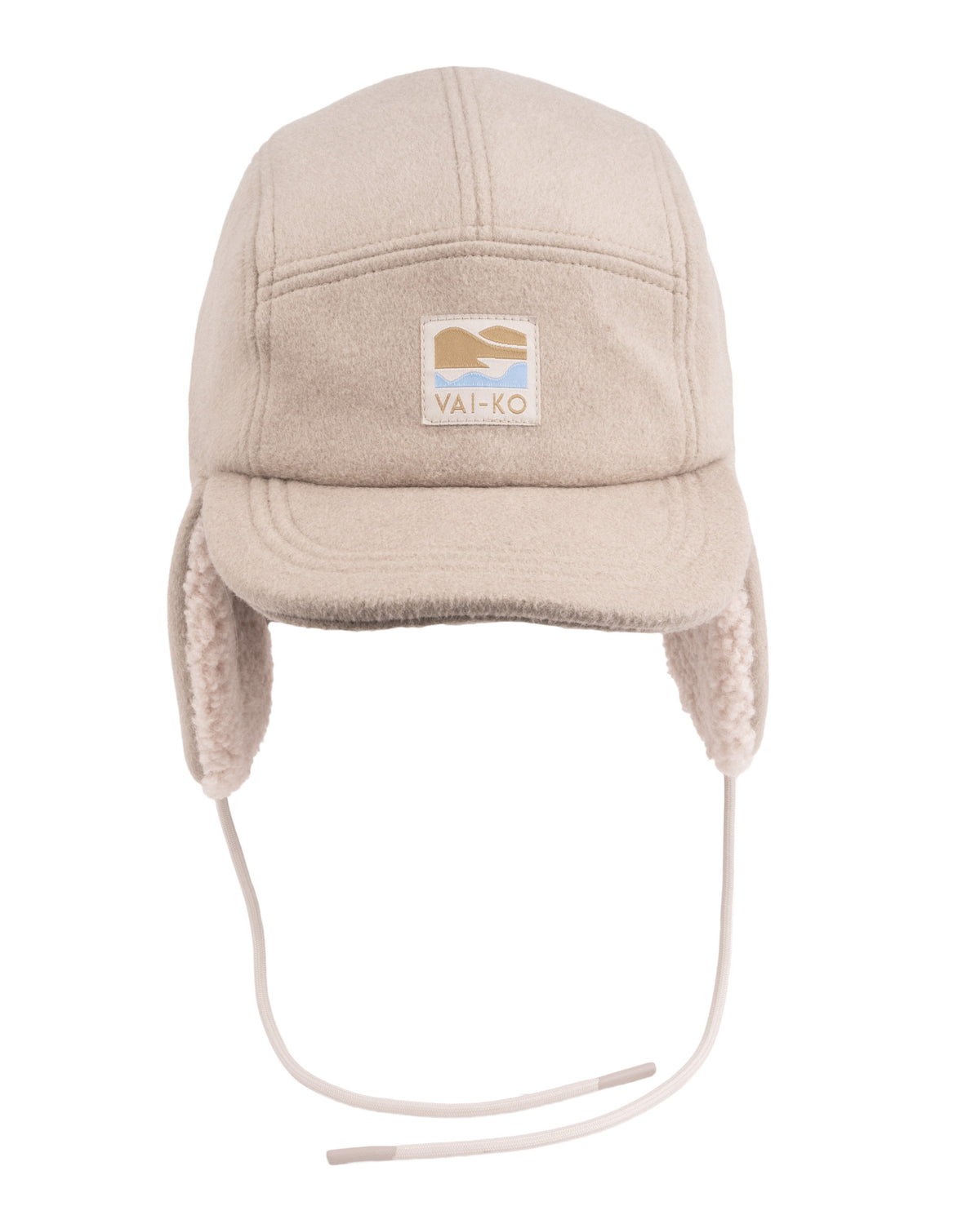 Beige winter hat with ear flaps, drawstrings, and a rectangular VAI-KO logo patch on the front.