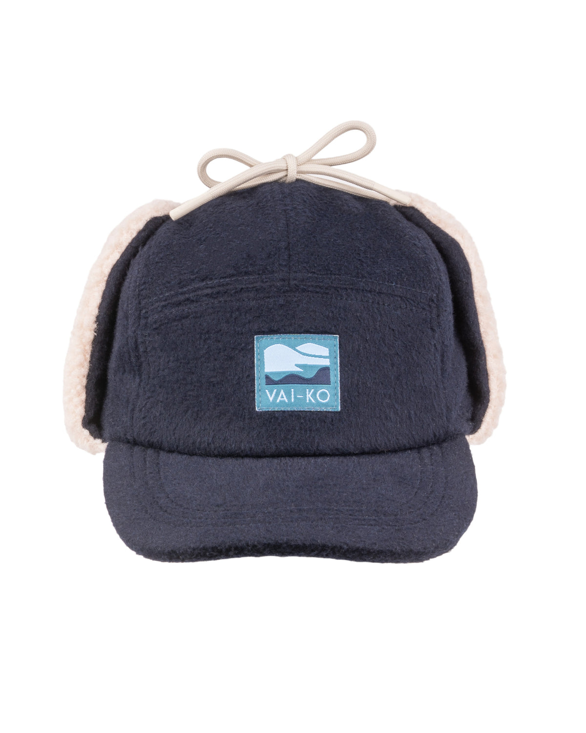 Navy blue fleece cap with ear flaps, a front patch reading VAI-KO, and a bow on top.