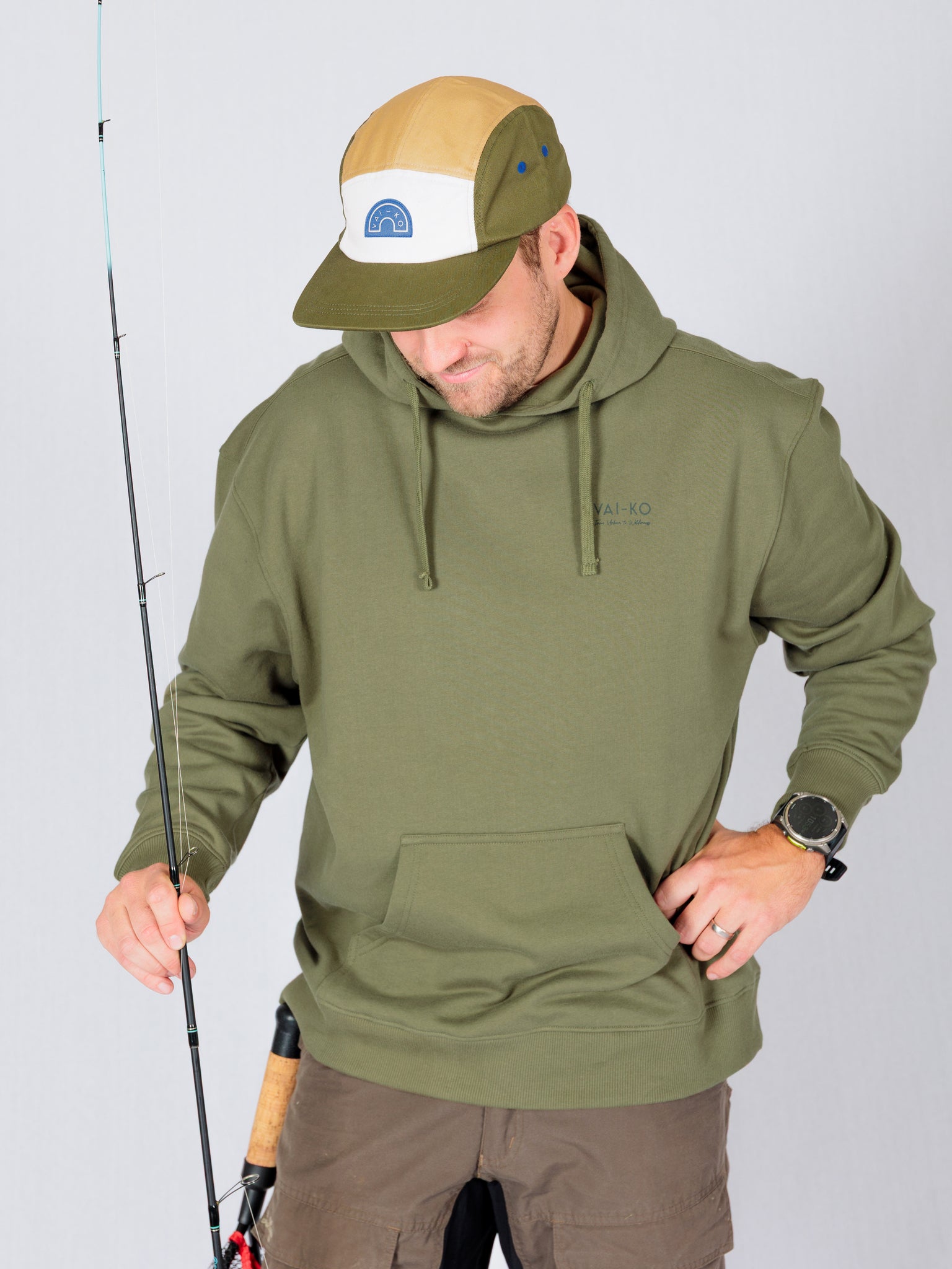A man in a green hoodie holding a fishing pole.
