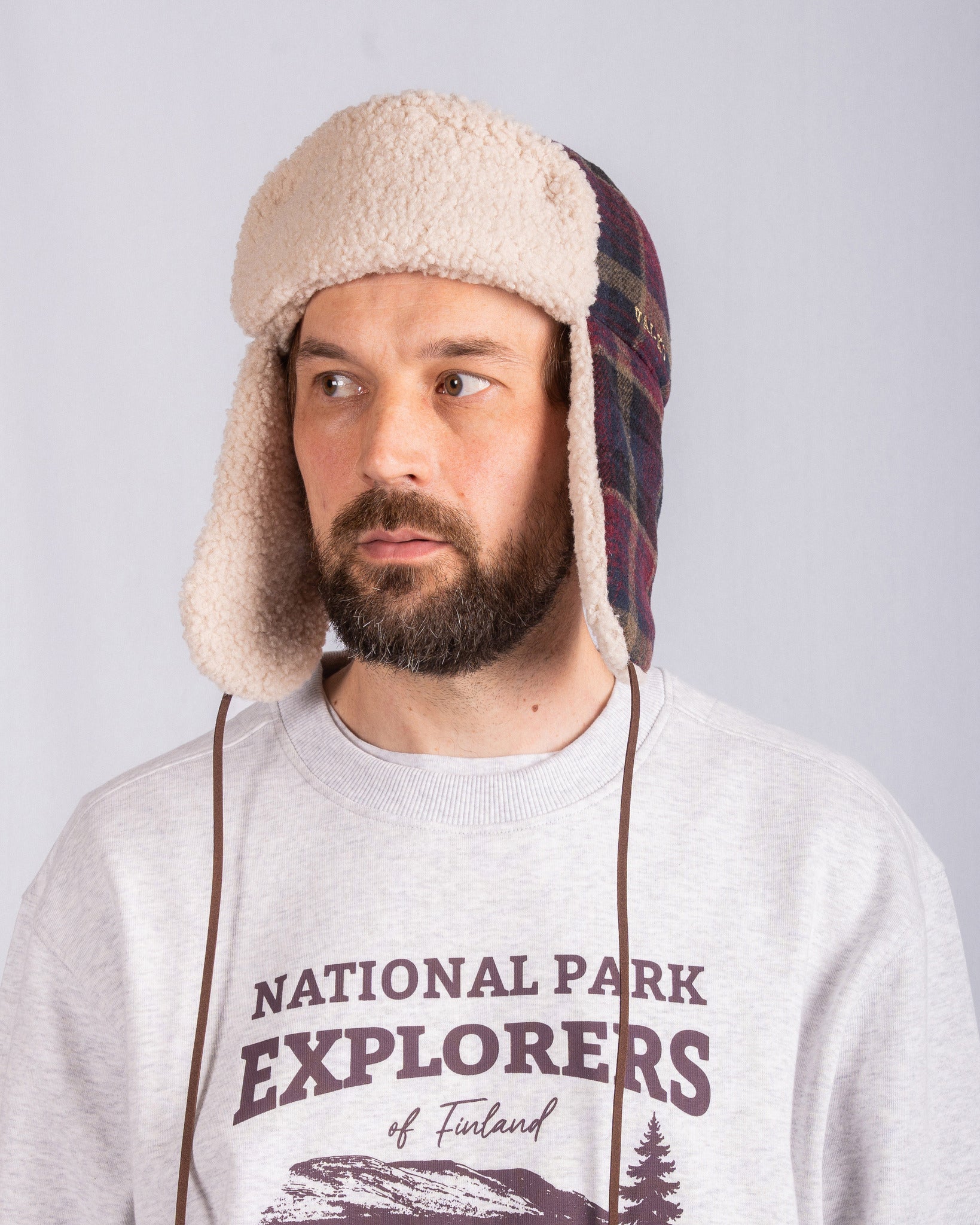 Bearded man in a trapper hat and National Park Explorers sweatshirt looking slightly to the side.