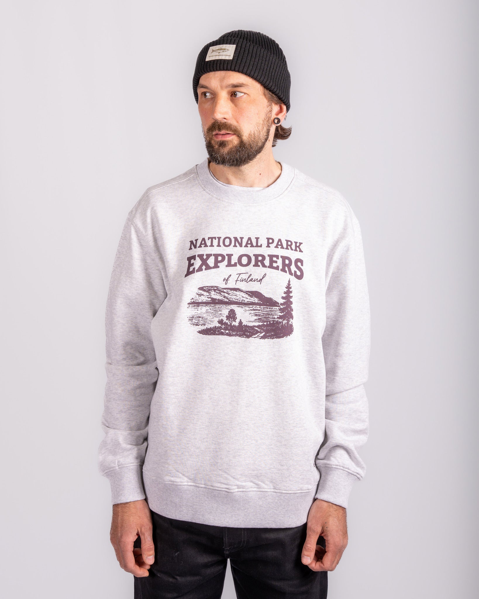 Man in a gray National Park Explorers sweatshirt and black beanie standing against a plain background.