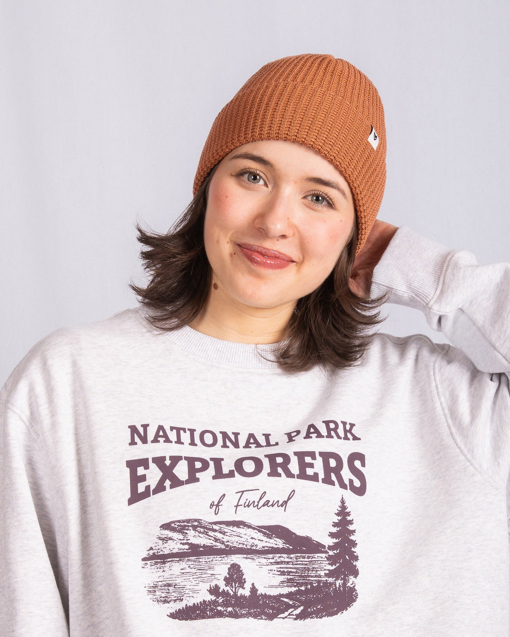 Woman in a brown knit hat and National Park Explorers of Finland sweatshirt smiling at the camera.