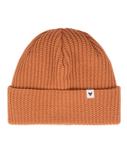 Rust orange knit beanie with a folded brim and a small white tag featuring a simple black design.